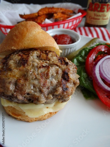 homemade grilled burger with melted white cheese fresh lettuce tomato red onion and pickle
