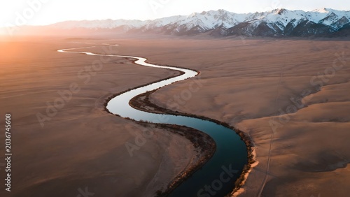 Winding river in desert with snow mountains