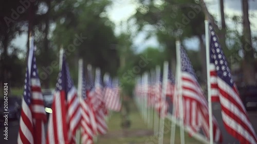 Slow motion cinematic footage of a row of American Flags Lining a Suburban Street with Bokeh Background and copy space