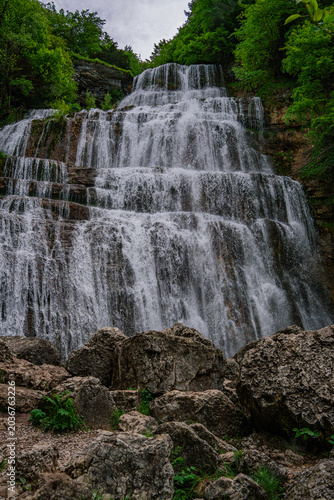 Drone photography of a massive waterfall with a man standing below for scale