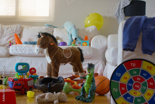 Photos Toys covering the floor and sofa, including a rocking horse, dinosaur, fire truc