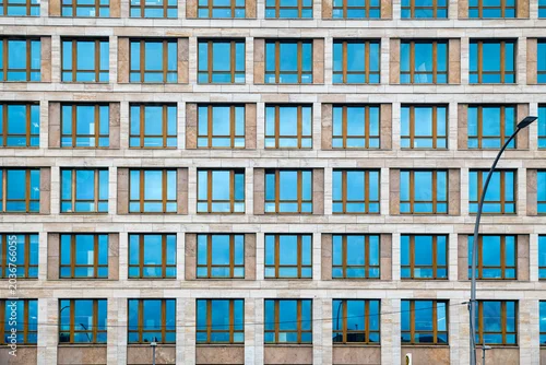 Fototapeta na wymiar A straight-on, flat lay style architectural photograph of a large building facade made of light beige stone tiles. The facade 