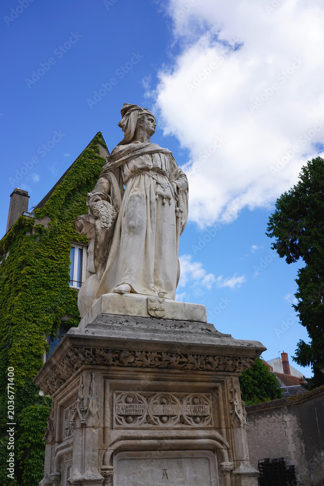 Obraz premium Statue of Jacques Cœur in Bourges, France, set against a lush ivy-covered building.
