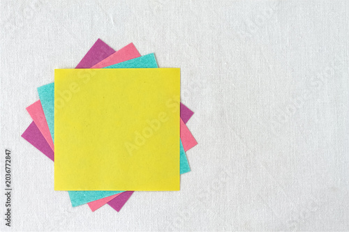 Colorful blank sticky notes stack on white linen background with copy space, multicolored paper reminder template.