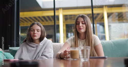Two Teenage Girls Enjoying Coffee and Conversation at a Cafe: A Bonding Moment of Friendship and Laughter