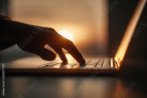 In a softly lit room, a person uses a laptop emphasizing focused work, comfortable indoor lighting, and everyday digital productivity in a calm workspace atmospher
