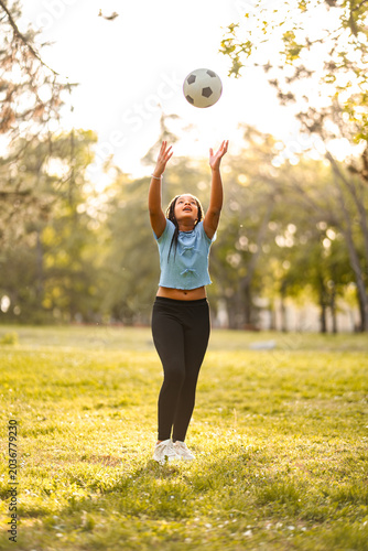 Young girl playing with soccer ball in park