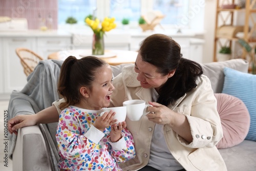 Εκτύπωση καμβά Grandmother and her granddaughter enjoying hot drinks together on sofa at home