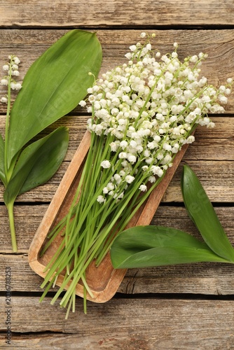 Beautiful lily-of-the-valley flowers on wooden table, flat lay