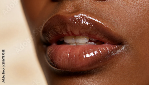 Close up of woman lips with glossy makeup. Macro shot of african american skin texture and reflection on gloss. Concept of skincare, beauty industry, cosmetics product and facial care.