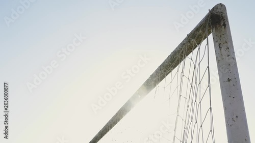 Football player scores winning goal as the soccer ball curves into the corner of the net. Street football scene in urban or rural area. Training match with focus on precision shot and childhood sports