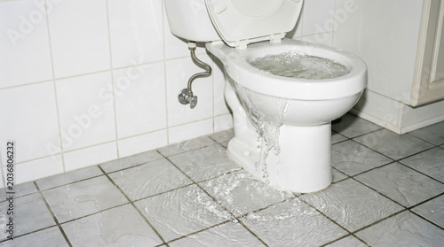 Overflowing toilet in bathroom with water on the floor. Toilet bowl overflowing causes water damage in home, creating an unpleasant situation. Concept bathroom maintenance and plumbing emergencies.