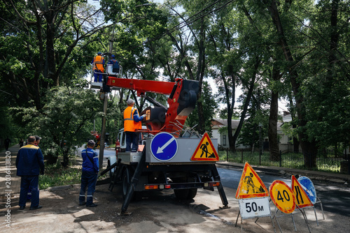 Group of electricians repairing power lines by using aerial lift platform