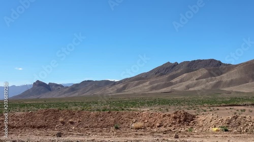 Atlas Mountains rising above arid Moroccan landscape under blue sky