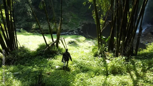 A traveler walks through a bamboo forest towards a hidden waterfall ravine.