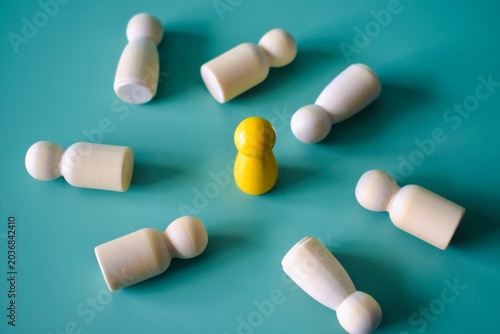 Fotografía Symmetrical high angle shot of a single yellow figure standing amidst scattered fallen white figures on a blue surface