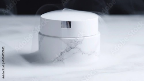 Serene white and marble-patterned cylindrical container gently enveloped by soft, mysterious wisps of vapor on a minimalist display