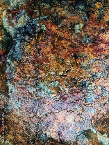 фотографія High-angle macro shot of a wet mineral ore surface concentrating vibrant iron oxide rust and dark copper stains