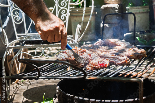 Parrilla con asado argentino de carne vacuna cocinándose sobre brasas durante reunión familiar de fin de semana