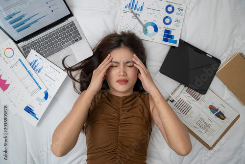 Overwhelmed woman with stress surrounded by financial graphs and documents