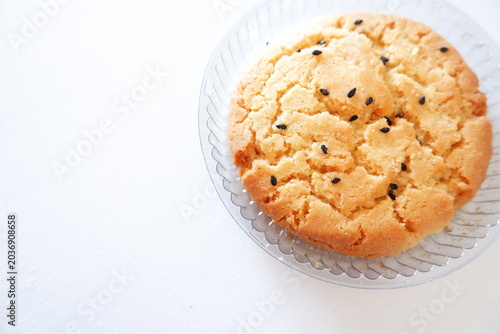 Vászonkép Close-up of crunchy sesame biscuit on white background, golden baked cookie with black sesame topping and crumbly texture
