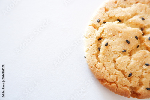 Photos Close-up of crunchy sesame biscuit on white background, golden baked cookie with black sesame topping and crumbly texture
