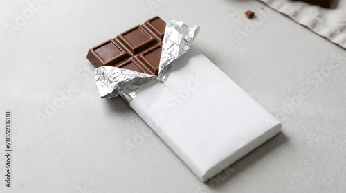A delicious and satisfying bar of rich dark chocolate, unwrapped and ready to be enjoyed, presented on a clean surface for a sweet indulgence
