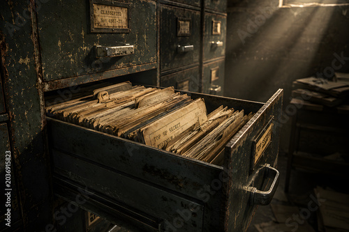An open metal filing cabinet drawer filled with old folders in a dark room