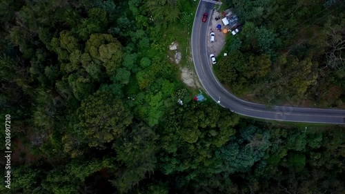 Aerial top-down view of cars driving on a winding forest road
