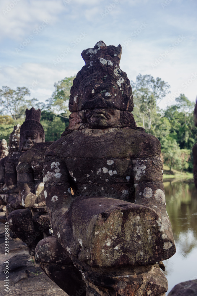 Fototapeta premium Ancient stone statues line the causeway to Angkor Wat temple complex in South Gate Angkor Thom, , Siem Reap, Cambodia. These figures guard the entrance to the sacred site.