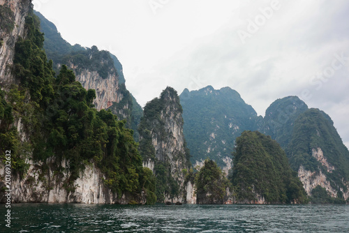 Dramatic limestone cliffs rising above emerald water in a tropical island landscape, kaosok thailand