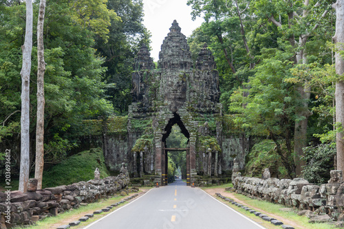 Картината върху платно The ancient stone gate of Angkor Thom North Gate, Siem Rep, Cambodia, stands majestically amidst lush jungle foliage, inviting visitors to explore the historic wonders of Siem Reap