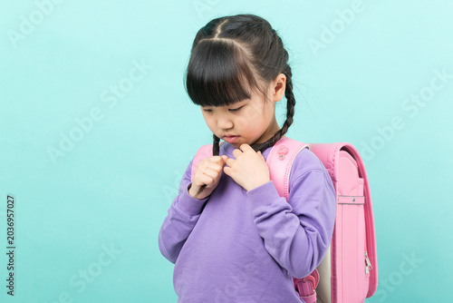 Valokuva An anxious Asian girl is seen fidgeting with her braids, looking down and displaying nervousness – a sign of back-to-school anxiety and childhood stress