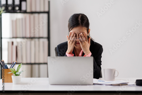 Fotografie Business woman overwhelmed by workplace stress and fatigue, rubbing dry eyes and