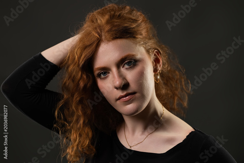 Young woman with red hair and blue eyes looking at camera in a studio