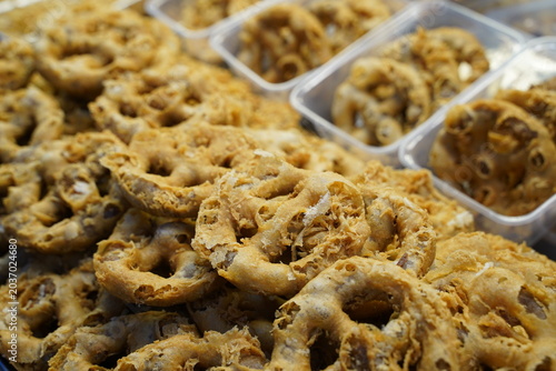 Display of golden brown crisp traditional Thai fried snacks, neatly stacked in a glass display at a local street food vendor.