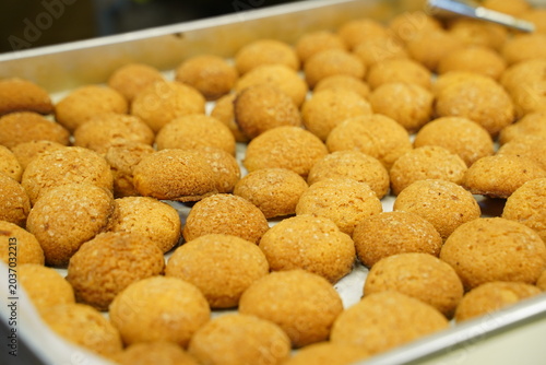 A large batch of golden crisp traditional Thai deep fried sweet potato balls (Khanom Kai Nok Kratha) displayed on a metal tray at a street food market stall.
