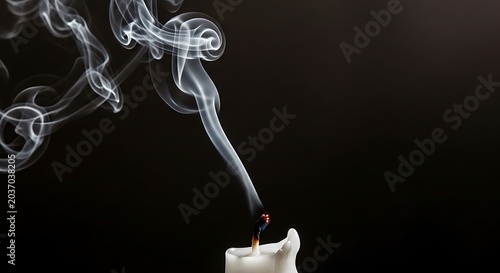 Wisps of white smoke rising from a recently extinguished candle