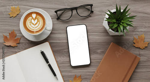 Modern workspace flat lay with latte art coffee, smartphone, notebook, glasses, and autumn leaves evoking cozy productivity and creative inspiration.