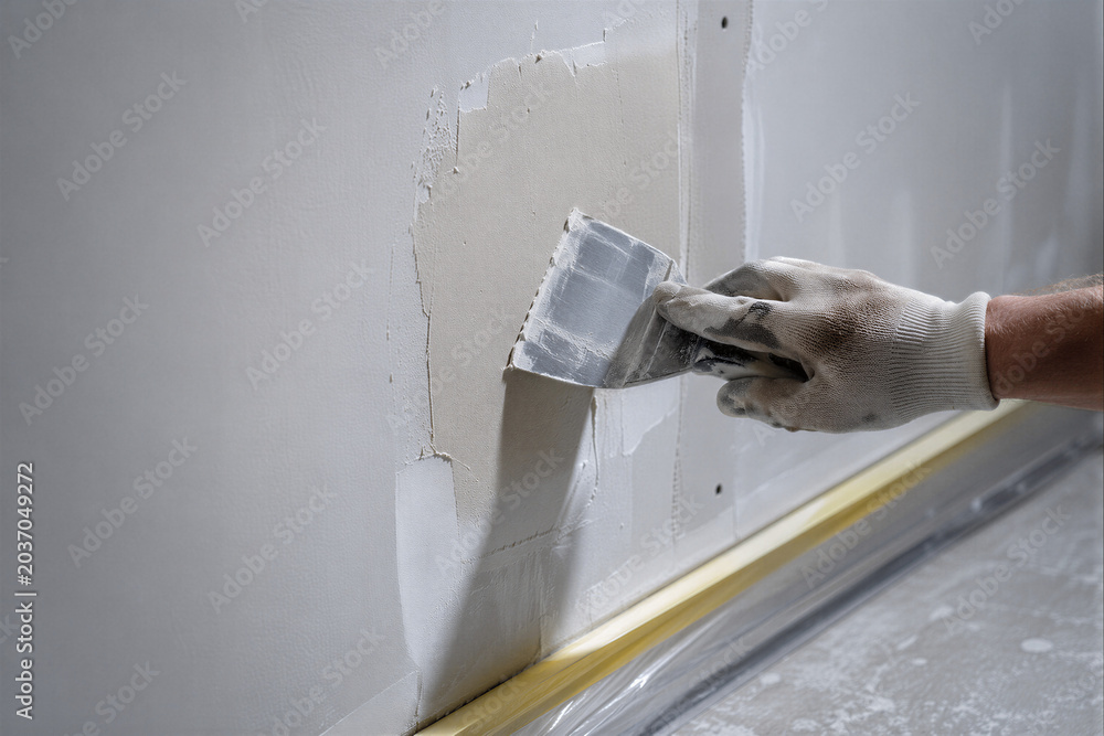 Naklejka premium Worker Applying Wall Filler During Drywall Repair as Home Renovation and Interior Finishing Concept