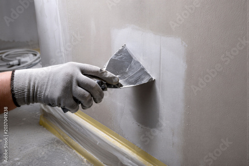 Applying Wall Filler with Putty Knife as Drywall Repair and Home Renovation Concept
