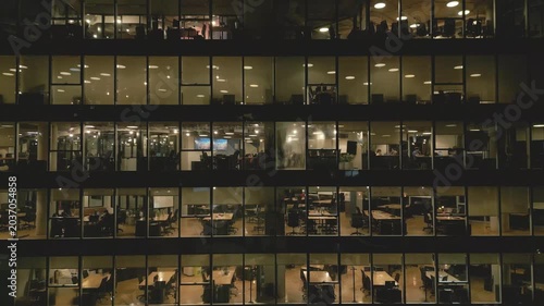Office workers in a tall building work late at night in a city