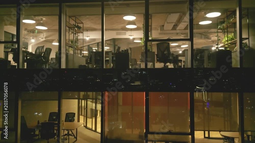 Office workers in a tall building work late at night in a city