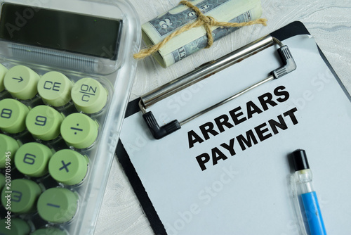 Photos Concept of arrears payment write on clipboard isolated on Wooden Table
