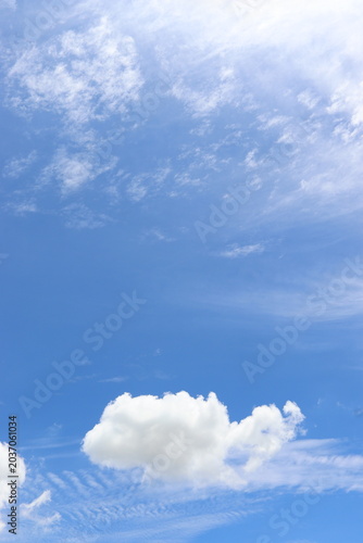 Bright blue sky with soft white clouds drifting peacefully on a sunny day, creating a calm and refreshing natural background.