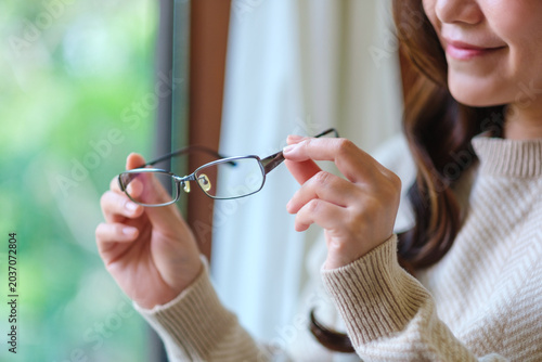 Fotografie Closeup image of a woman holding glasses at home