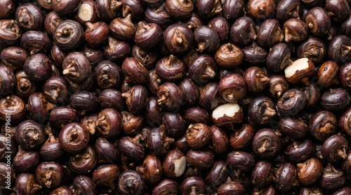 Fresh raw water chestnuts pile background displaying natural dark purple skins and crisp white flesh for healthy asian cooking ingredients and organic produce