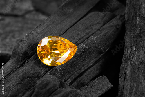 yellow gemstone on black coal background, close up shot