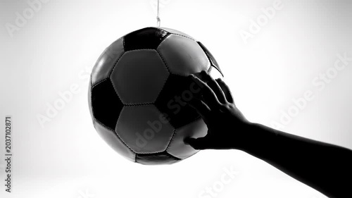 Silhouette of hand touching soccer ball against white.