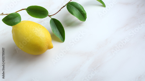 Fresh lemon with green leaves on a marble surface, showcasing vibrant yellow against a clean white background.